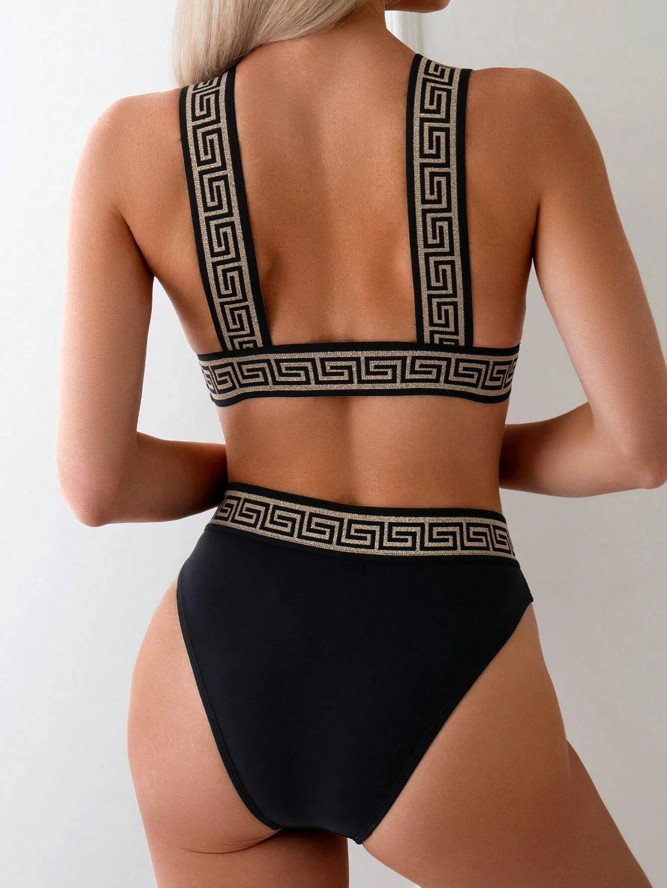 Black high-waisted bikini with gold Greek key trim, showcasing elegance and style. Confidently show your beach flair